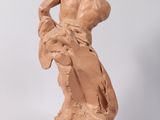 statue of a man sitting on a rock with his hands on his hips