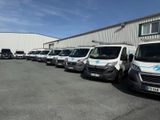 de nombreuses camionnettes garées en rang devant un immeuble