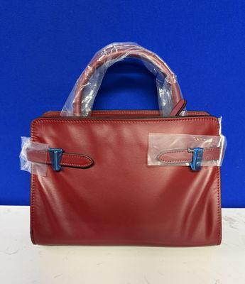 a red leather handbag with clear plastic handles on a table