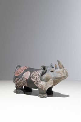 une figurine de rhinocéros posée sur une surface blanche