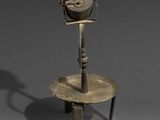 un vieil objet en métal posé sur un socle, avec l'ombre d'une personne