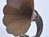 un vieux gramophone posé sur un support, sur fond blanc