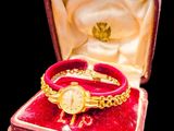 a red velvet case with a gold watch in it