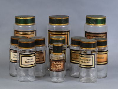 six bocaux en verre remplis de différents types de médicaments, posés sur une surface blanche