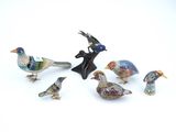five figurines of birds sitting on a white surface