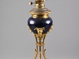un vase bleu et or posé sur un socle, sur une surface grise