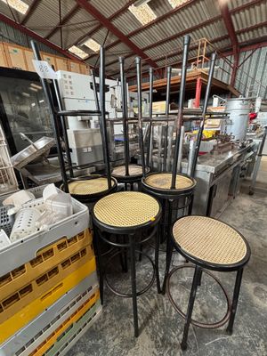 Plusieurs chaises et tabourets sont empilés dans un entrepôt
