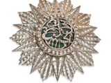 un gros plan d'une broche en argent avec un cœur vert