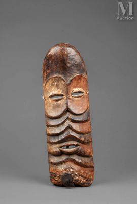 a carved wooden mask with a face on a gray background