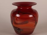 a red glass vase with a swirl design on it