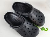 pair of black clogs with holes on them sitting on a white surface