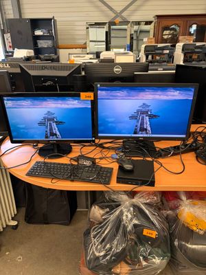 two computer monitors sitting on top of a wooden desk
