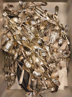 une boîte remplie d'une multitude de cuillères et de fourchettes en argent