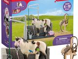 toy horses are standing in a stable with a horse on the ground