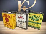 three old oil cans sitting on a table next to each other
