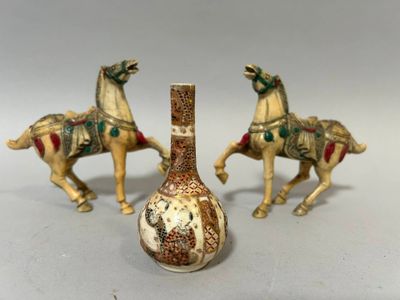 trois figurines de chevaux et un vase posés sur une table