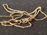 a gold chain that is laying on a black surface