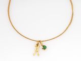 a gold plated necklace with a green stone and initial charm