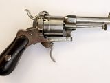 un vieux revolver avec une poignée en bois sur une surface blanche