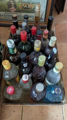 de nombreuses bouteilles d'alcool posées dans une boîte par terre
