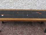 une table avec un plateau en carrelage noir et un piètement en bois