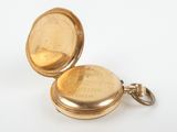 an antique gold pocket watch sitting on a white surface