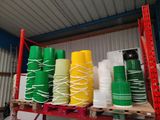 Plusieurs piles de gobelets en plastique sont empilées sur une étagère dans un entrepôt