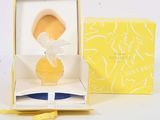 une petite figurine représentant une femme en robe jaune, dans une boîte jaune