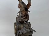statue of a woman sitting on top of a barrel with a bird on it