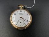 une montre de poche en or avec une chaîne, posée sur un fond noir