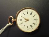 a gold pocket watch with roman numerals and a tassel