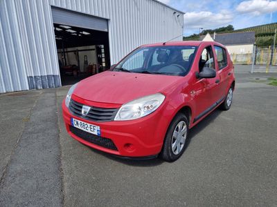 La petite voiture rouge est garée devant un immeuble.