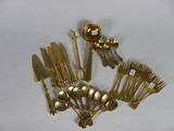 a lot of gold plated silverware on a white table