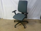 une chaise de bureau bleue posée devant un fond blanc
