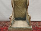 an old chair with a green velvet upholstered seat on a red rug