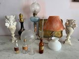 une table sur laquelle se trouvent une lampe, un abat-jour, un vase, une bouteille et d'autres objets
