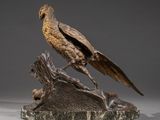 bronze sculpture of a bird perched on a tree stump on a gray background