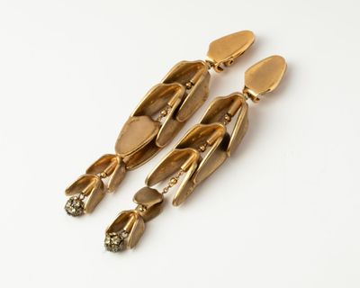 an image of a pair of gold earrings on a white surface