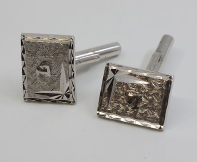 two silver cufflinks with a square design on them