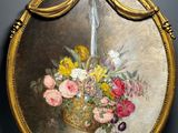 painting of a basket of flowers in a gold frame on a wall