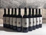 six bottles of wine are lined up in a row against a stone wall