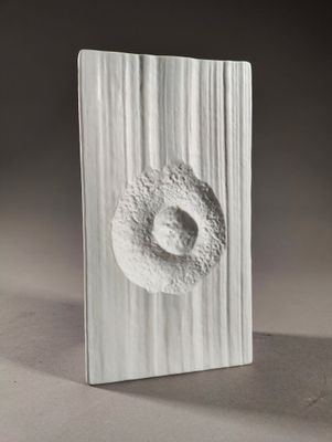 a white sculpture of a doughnut on a wooden block