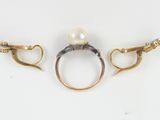 two rings with pearls and gold chains on a white surface