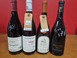 quatre bouteilles de vin sont alignées sur une table en bois