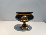 a black and gold vase on a white table