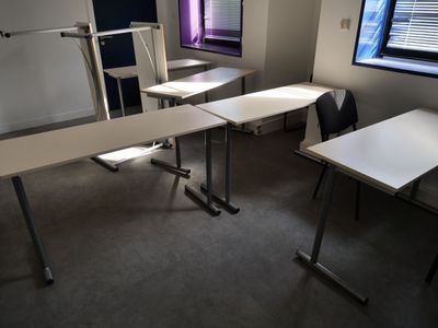 tables and chairs in a room with a window in the background