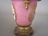 a pink vase with gold decoration on it on a stand