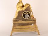 a gold clock with a statue on top of it
