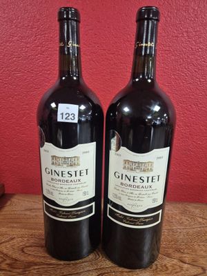 two bottles of wine sitting on top of a wooden table next to a red wall