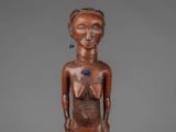 a wooden statue of a woman with a blue flower on her chest